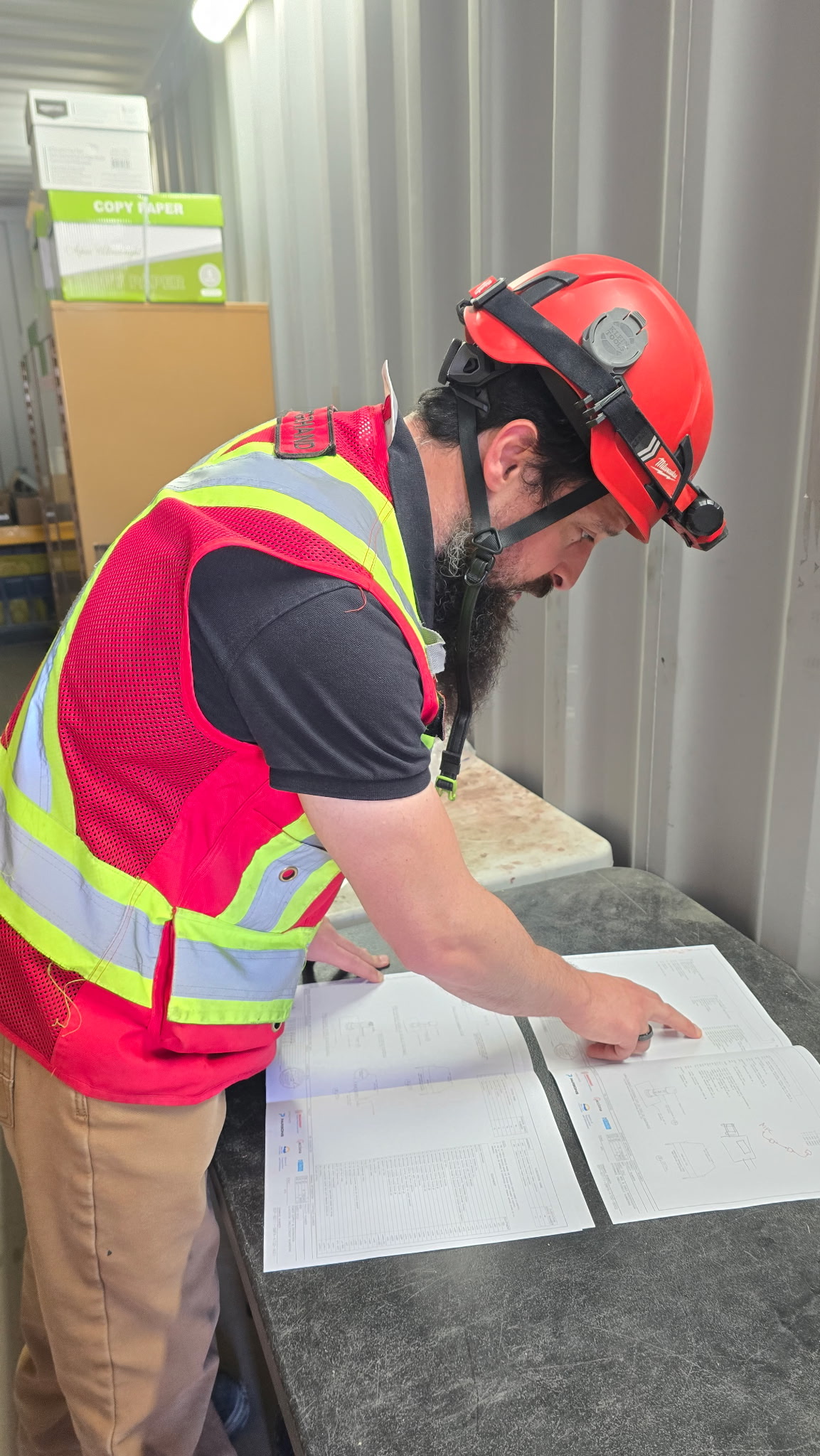Abdul reviewing electrical paperwork in his trailer on the jobsite.