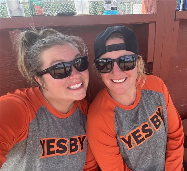A selfie with two women in the dugout at a baseball game.